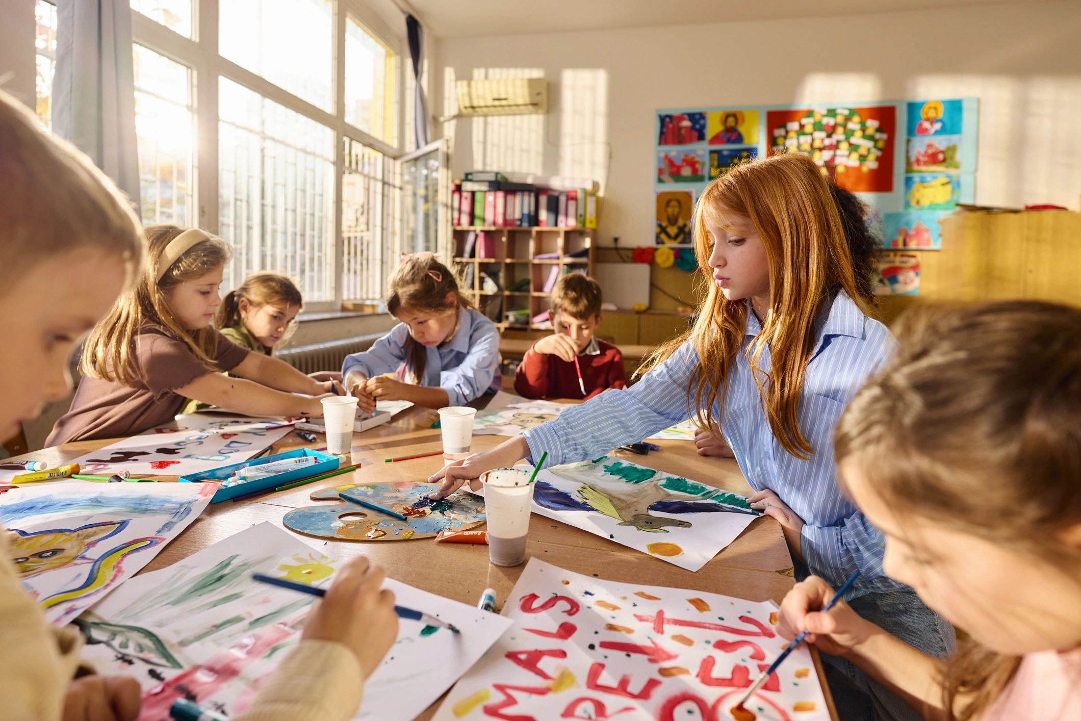 Children painting together in a bright classroom
